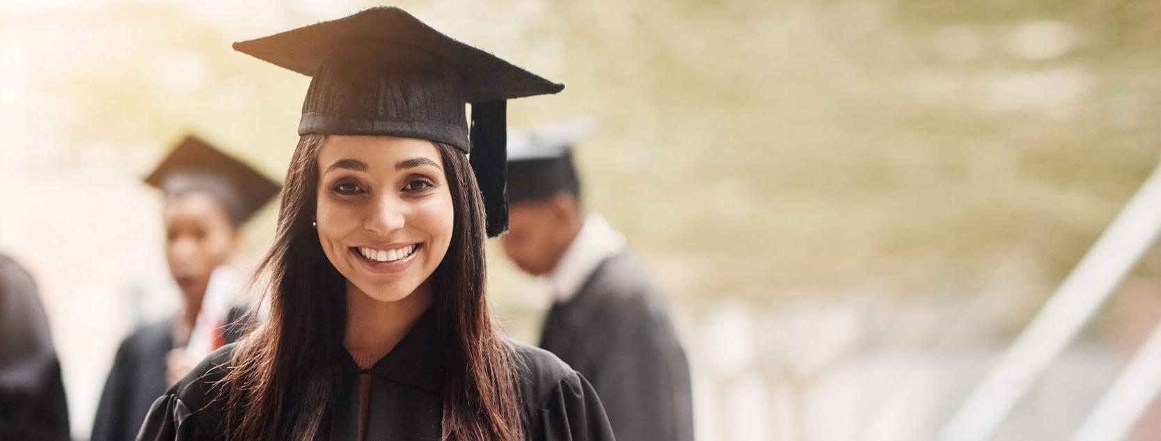 A smiling woman in her graduation cap and gown.